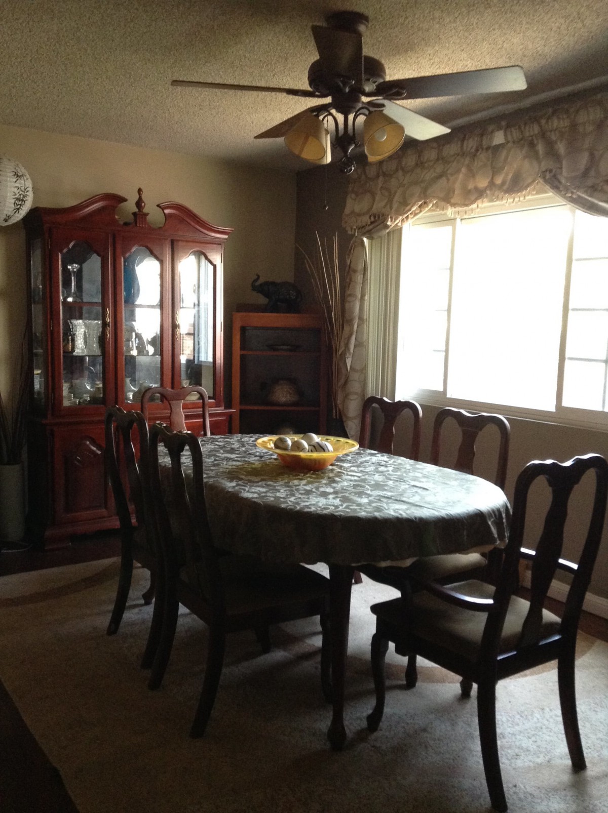 A cozy dining room with a large table, surrounded by chairs and illuminated by natural light from the window.