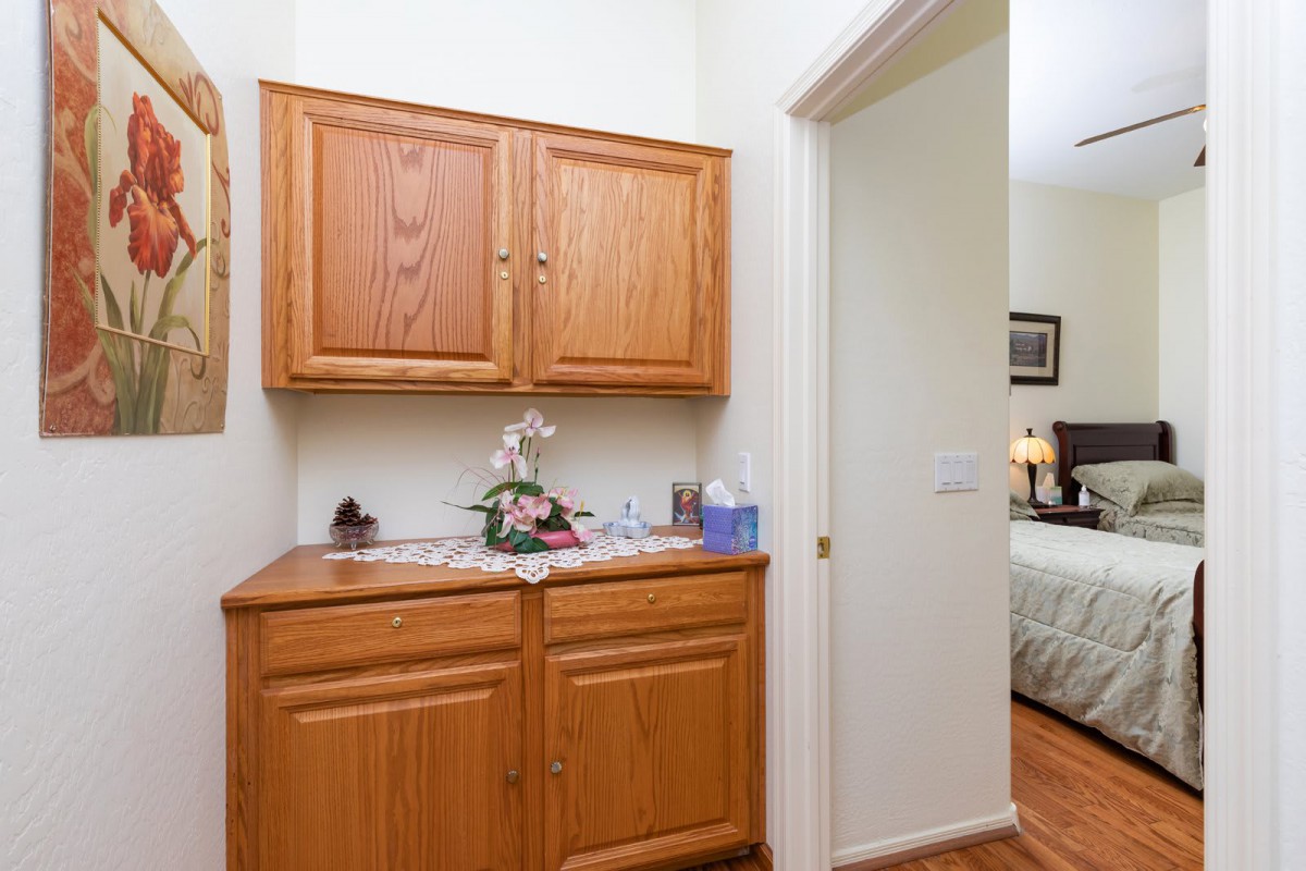 A hallway with wooden cabinets leading to a bedroom.