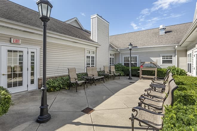 A sunny outdoor patio area with chairs and lamp posts next to a building.