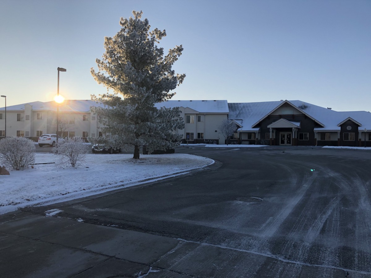 A snowy landscape with a building at sunrise.