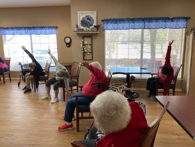 A group of seniors participating in a seated yoga session at a community center.