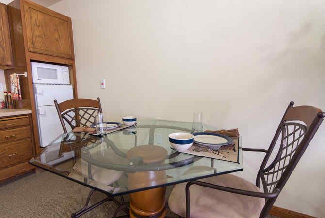 A glass dining table with chairs and dinnerware set in a kitchen area.
