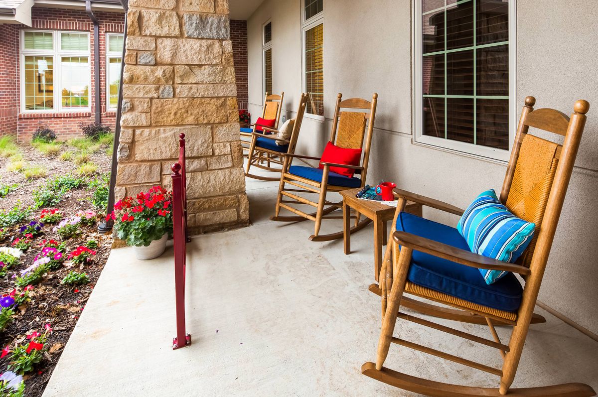 A cozy porch with rocking chairs adorned with cushions, offering a relaxing outdoor seating area next to vibrant flowers.