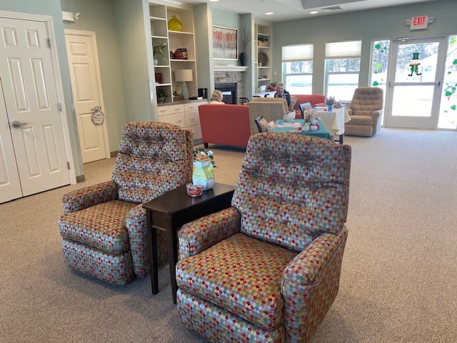 A cozy living room featuring patterned recliner chairs and a well-organized shelving unit in the background.