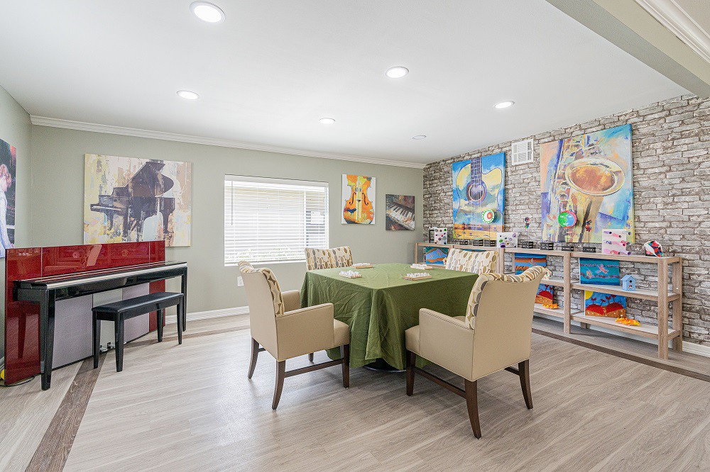 A modern dining area featuring an artfully decorated wall, a table with a green tablecloth, and beige chairs.
