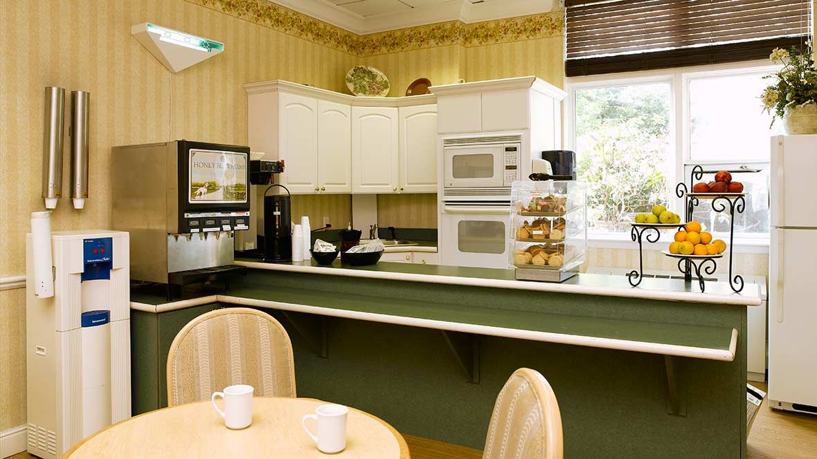 A cozy kitchen interior with white cabinets, built-in appliances, and a small dining table.