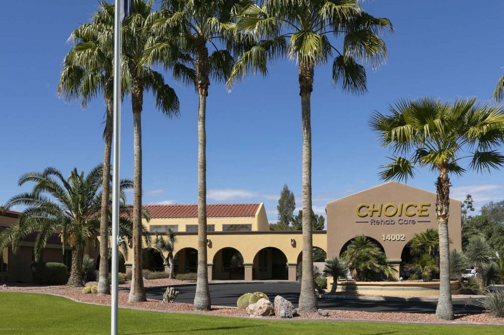A commercial building surrounded by tall palm trees under a clear blue sky.
