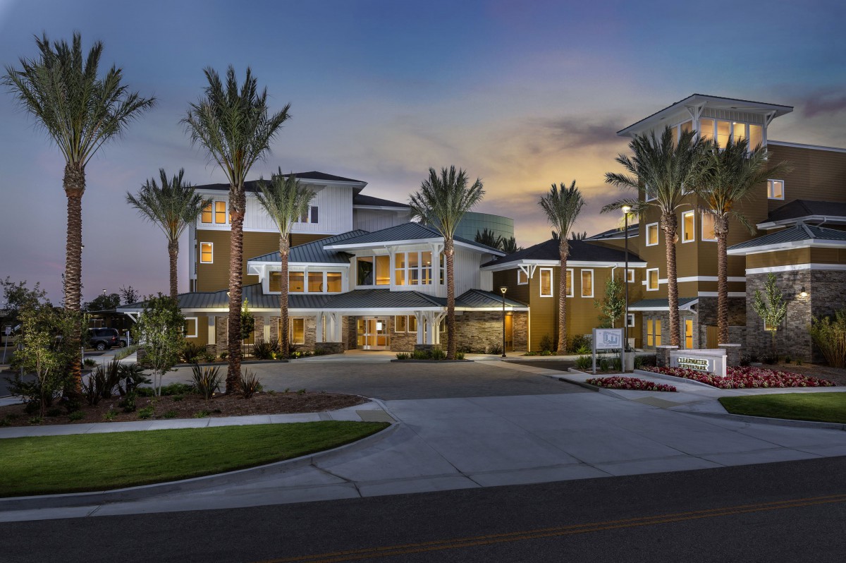A modern residential building with palm trees at dusk.