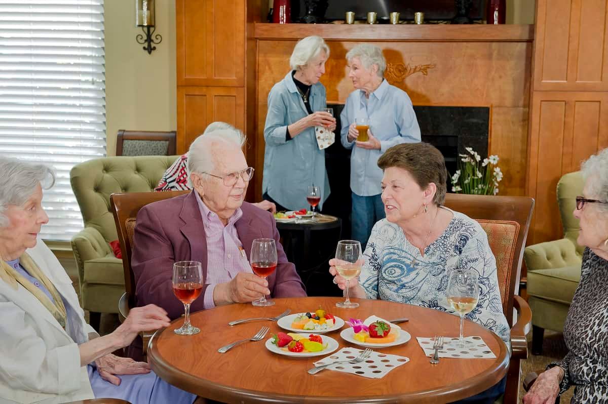 A group of seniors enjoying a social gathering with wine and conversation.