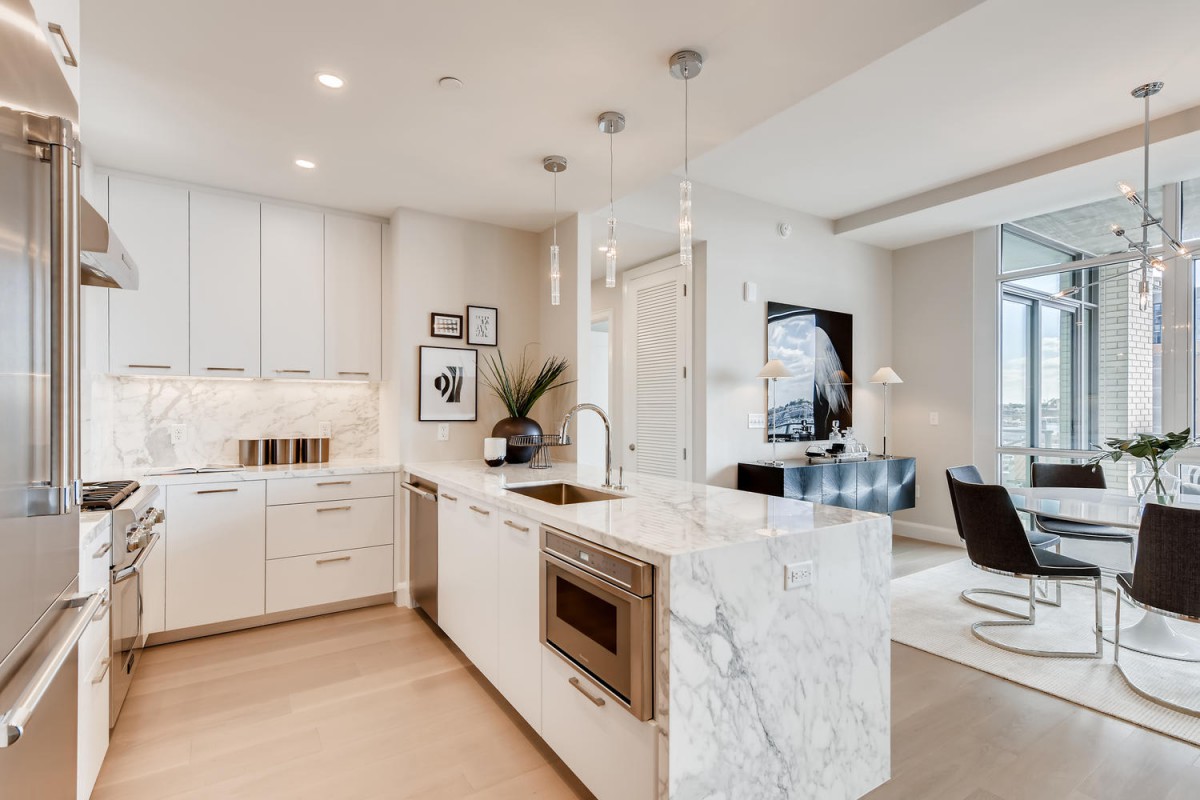 A modern open-concept kitchen with marble countertops and pendant lighting, seamlessly connected to a stylish living area.