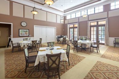 A spacious dining area with elegantly set tables and chairs, featuring warm lighting and a cozy ambiance.