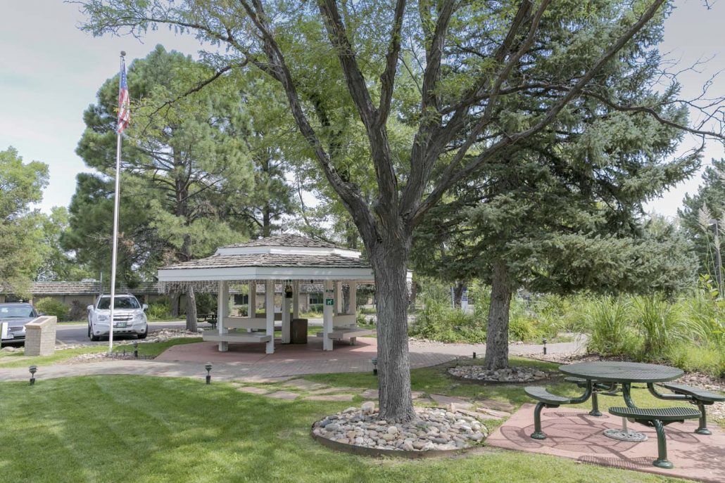 A peaceful park scene with a gazebo surrounded by trees and greenery.