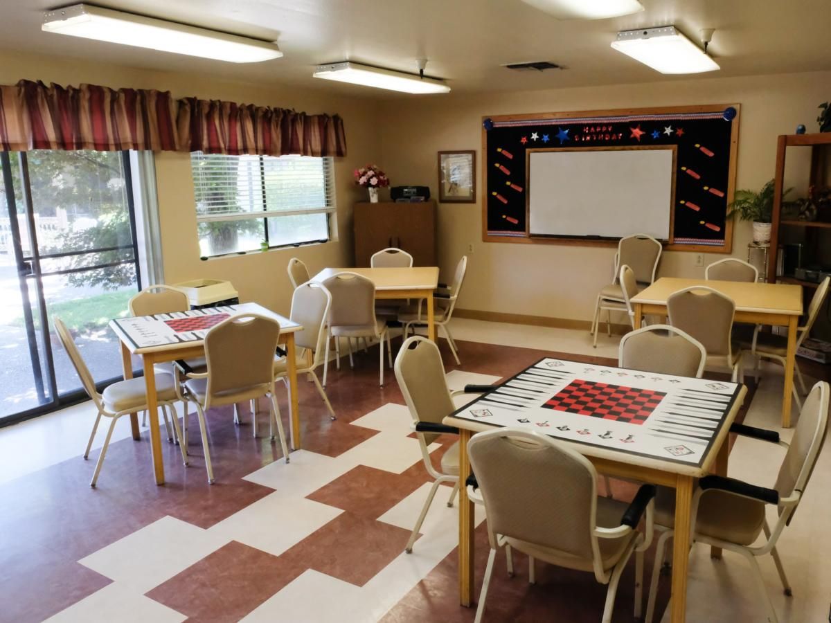 An empty classroom with tables and chairs arranged, featuring a projector screen.