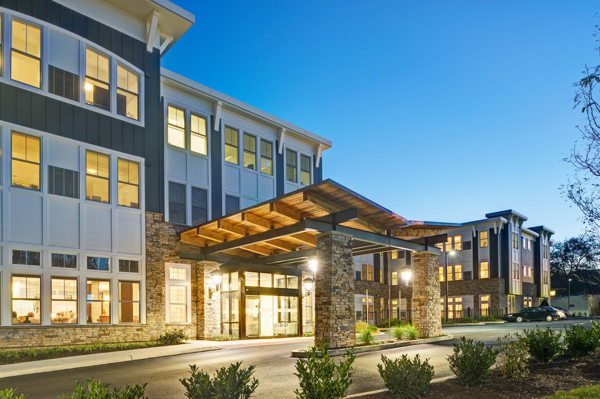 A modern building with illuminated windows and a welcoming entrance at dusk.