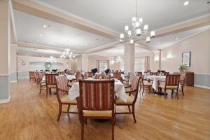 A spacious, elegantly decorated dining area with multiple tables and chandeliers overhead.