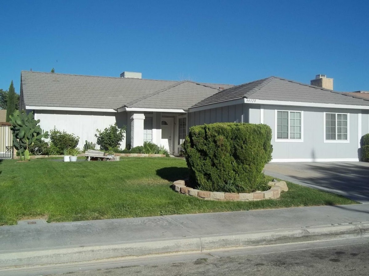 A suburban house with a well-maintained lawn under a clear blue sky.
