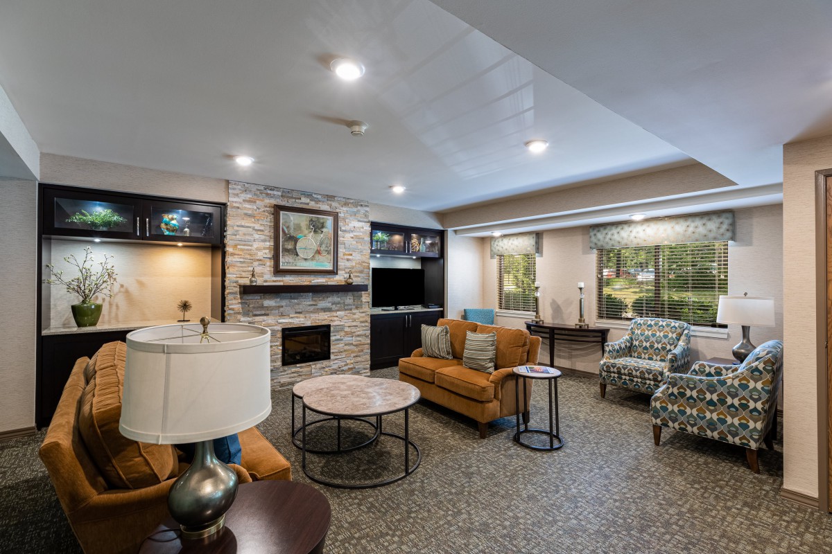 A modern and cozy living room featuring a stone fireplace, comfortable seating, and large windows.