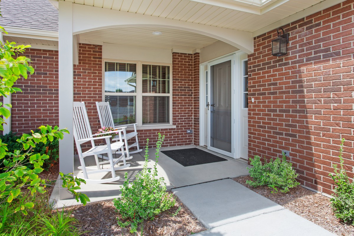 A cozy brick porch with rocking chairs and greenery.