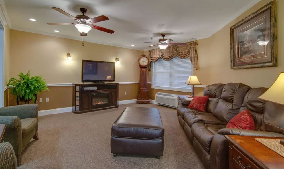 A cozy living room with a large sofa, coffee table, ceiling fans, and a television.