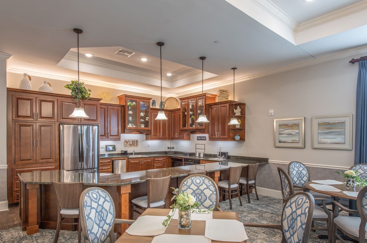A modern kitchen with wood cabinets, pendant lighting, and a connected dining area.