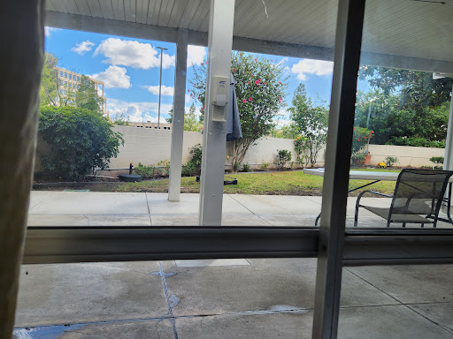 A serene outdoor view through a window, featuring bright blue skies and well-maintained greenery.