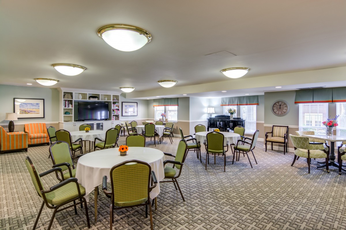 A well-lit dining area with multiple tables and chairs, featuring a television and decorative elements.