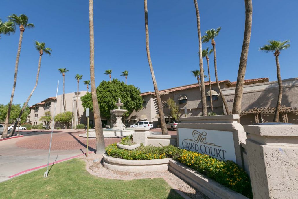 Entrance to a hotel with palm trees and a fountain.