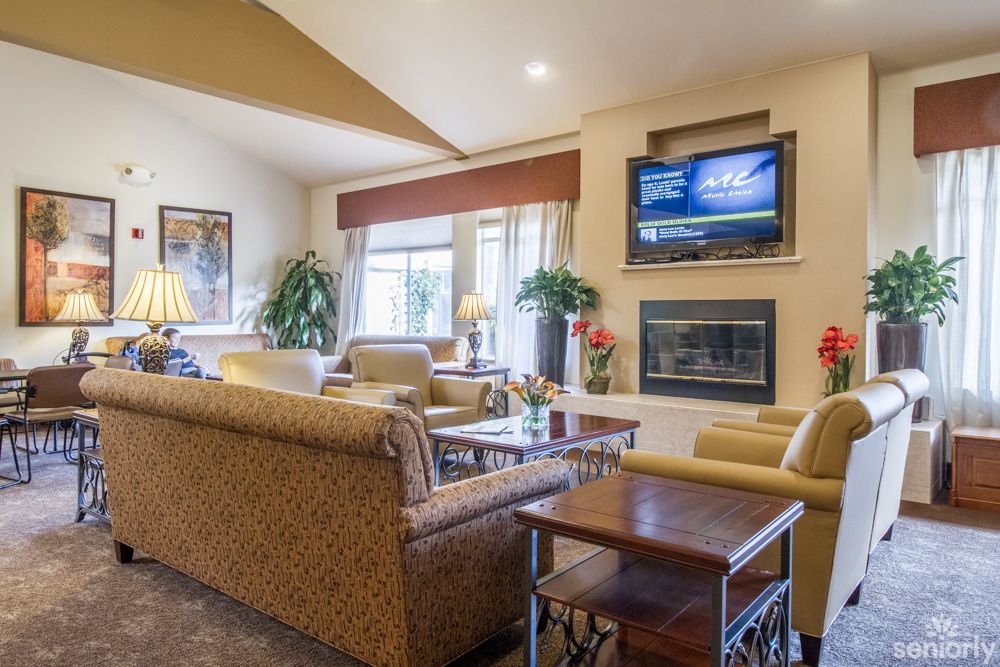 A cozy living room with a fireplace, comfortable seating, and a mounted television.