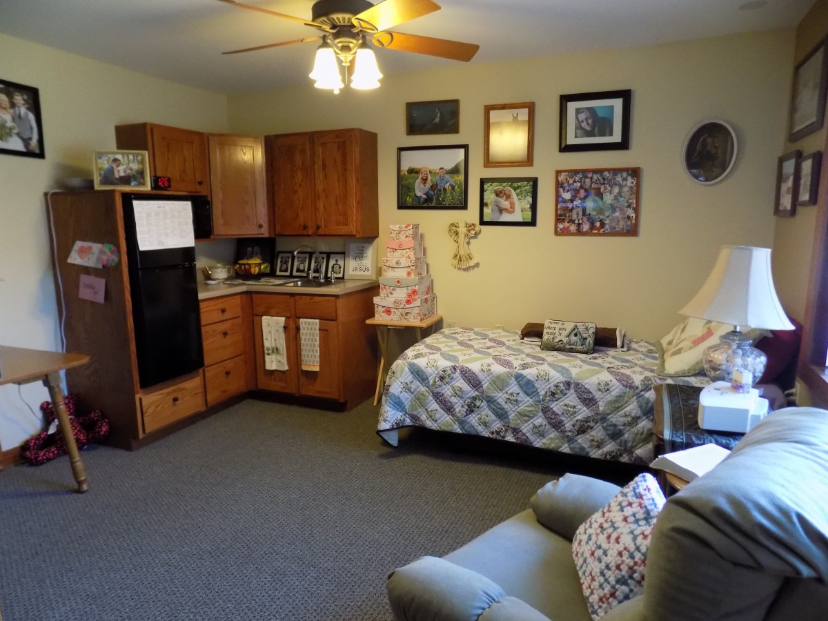 A cozy studio apartment with a small kitchen area, single bed, and comfortable seating.