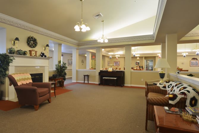 A cozy living room interior featuring a fireplace, piano, and comfortable seating.