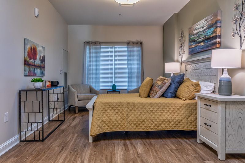 A cozy modern bedroom with wooden flooring, featuring a neatly made bed and decorative accents.