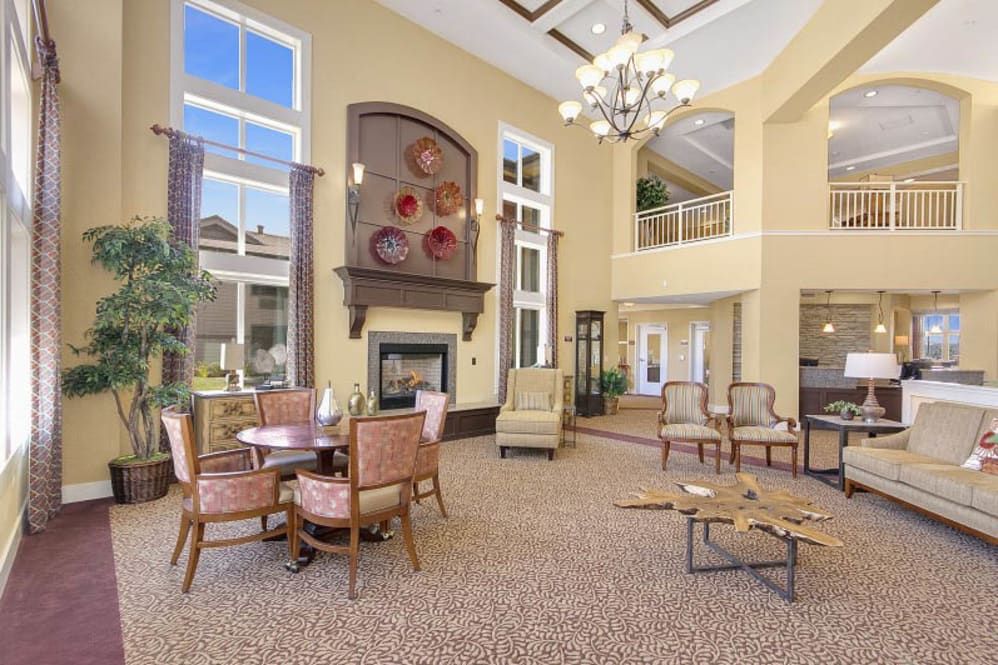 A spacious and well-lit lobby featuring a fireplace, chandelier, and comfortable seating.