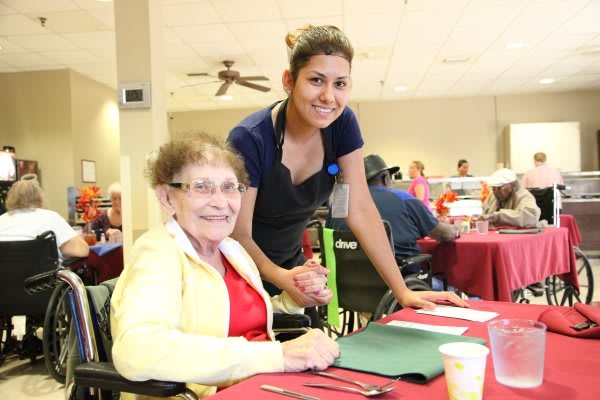 A caregiver assists an elderly woman in a community setting.