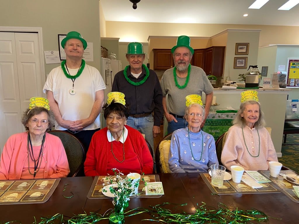 A group of seniors celebrating St. Patrick's Day with festive hats and decorations.