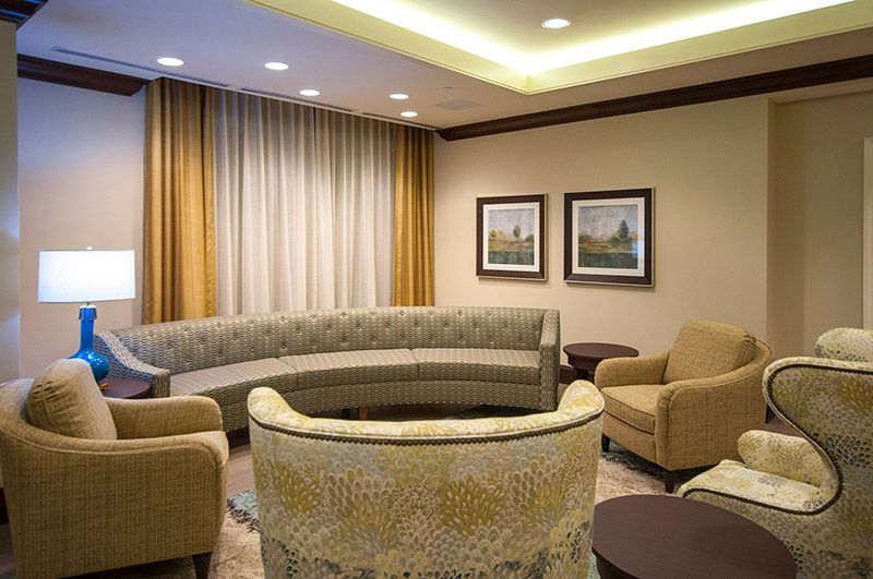 A modern living room with curved sofas, armchairs, and framed artwork on the walls.