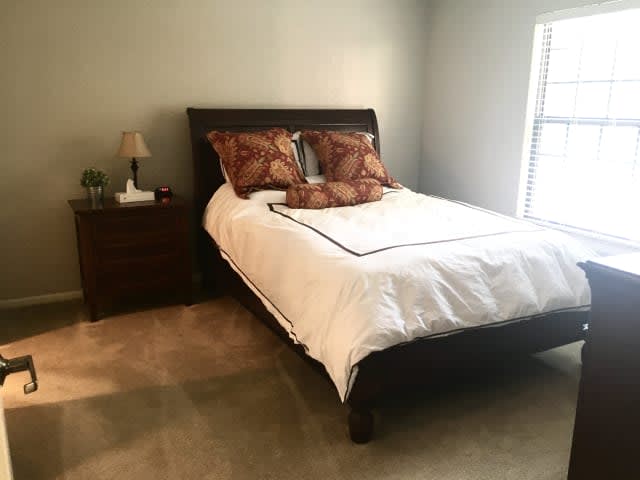 A tidy bedroom with a neatly made bed and nightstand.
