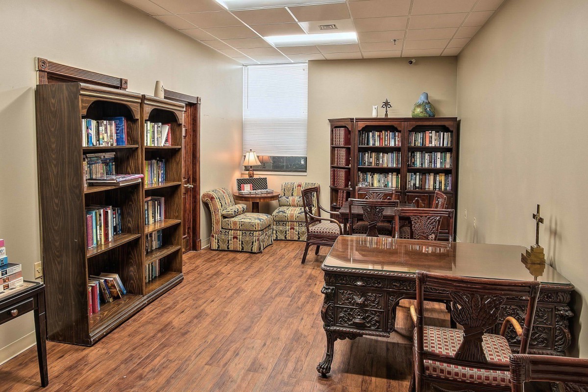 A cozy library reading room with wooden bookshelves and comfortable armchairs.