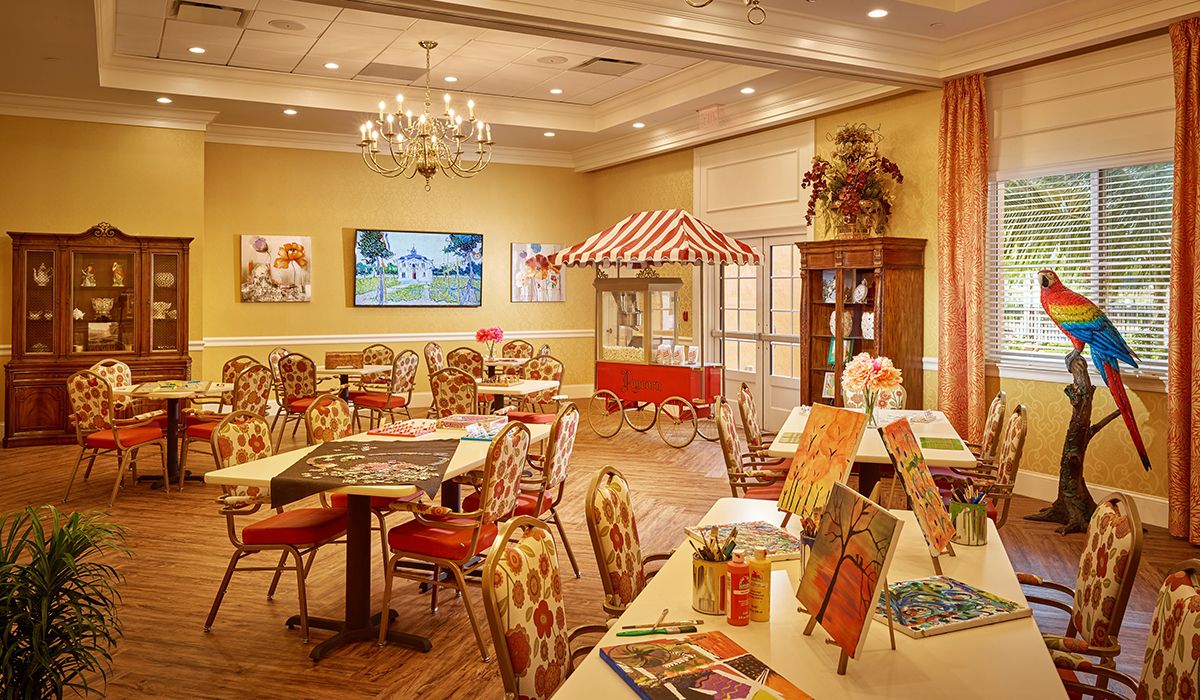 A cozy and colorful interior setting with dining tables, art supplies, and a warm ambiance.