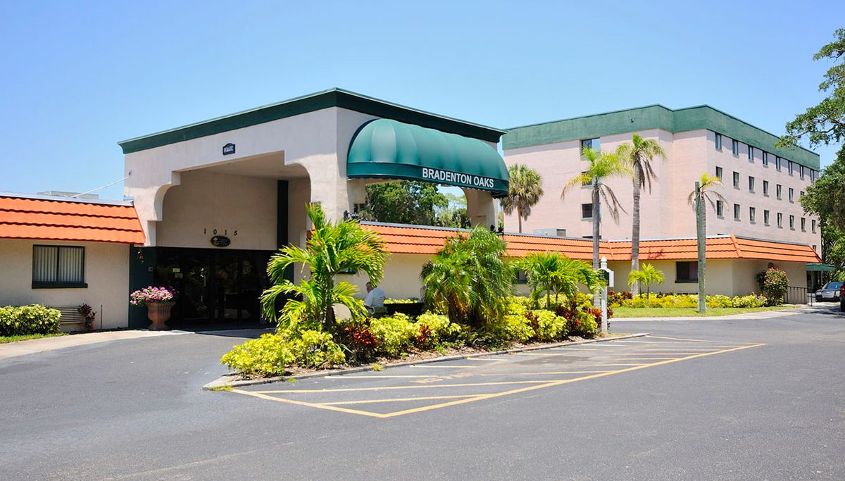 Hotel entrance with tropical landscaping and palm trees.