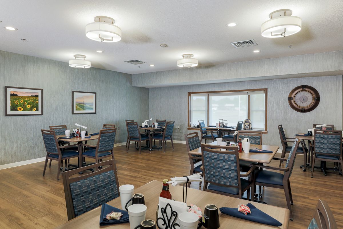A modern dining room with neatly arranged tables and chairs, illuminated by stylish ceiling lights.
