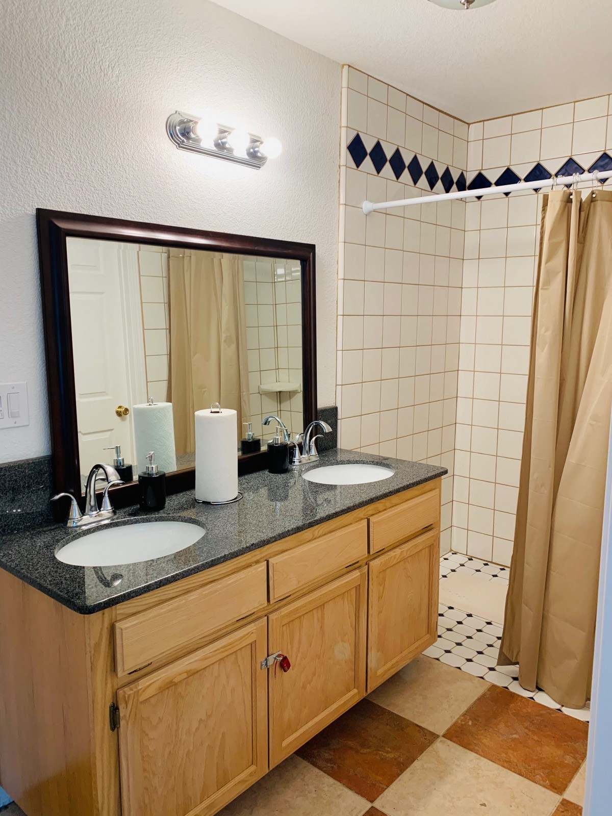 A bathroom with a double-sink vanity and a shower area with a curtain.