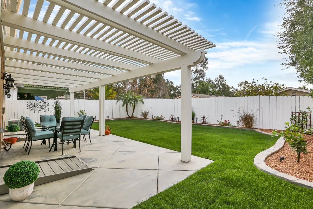 A peaceful backyard with a pergola-covered patio and well-maintained lawn.