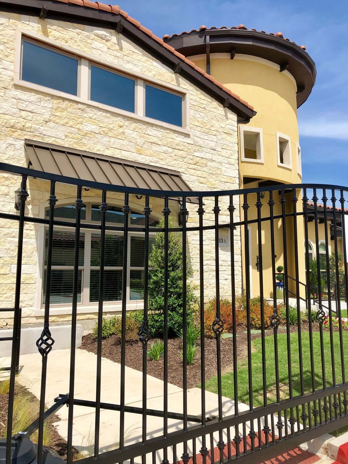 A modern house with a stone facade and an iron fence in front.