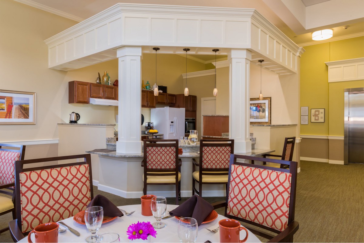 A cozy dining area with a kitchen in the background featuring elegant chairs and a well-set table.