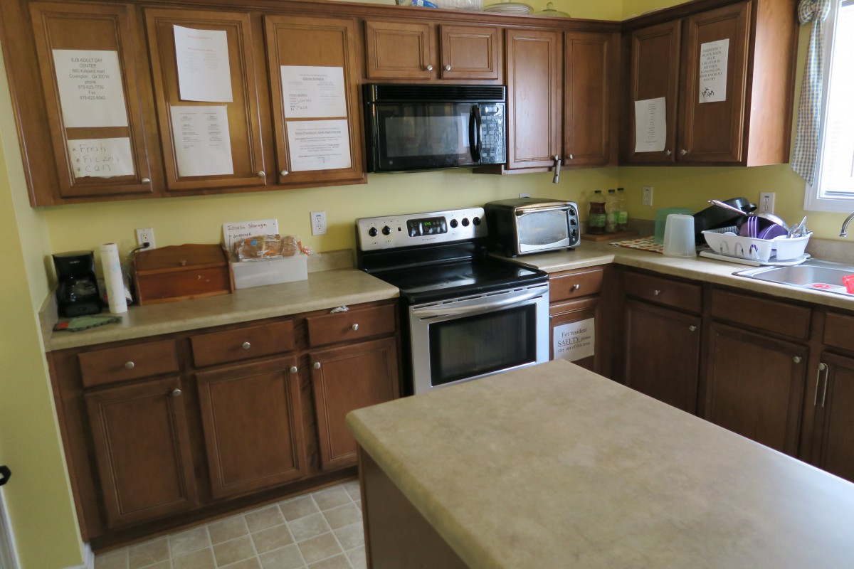 A kitchen with wooden cabinets, featuring a stove, microwave, and countertop appliances.