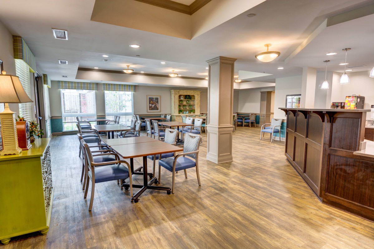 A spacious and well-lit dining area with modern furnishings and wooden flooring.