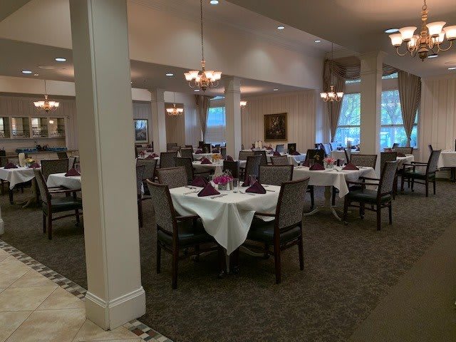 An elegant dining room with set tables and chandeliers.