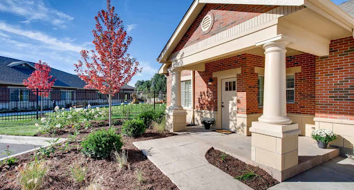 A charming building with a welcoming entrance, surrounded by landscaped gardens and vibrant trees.