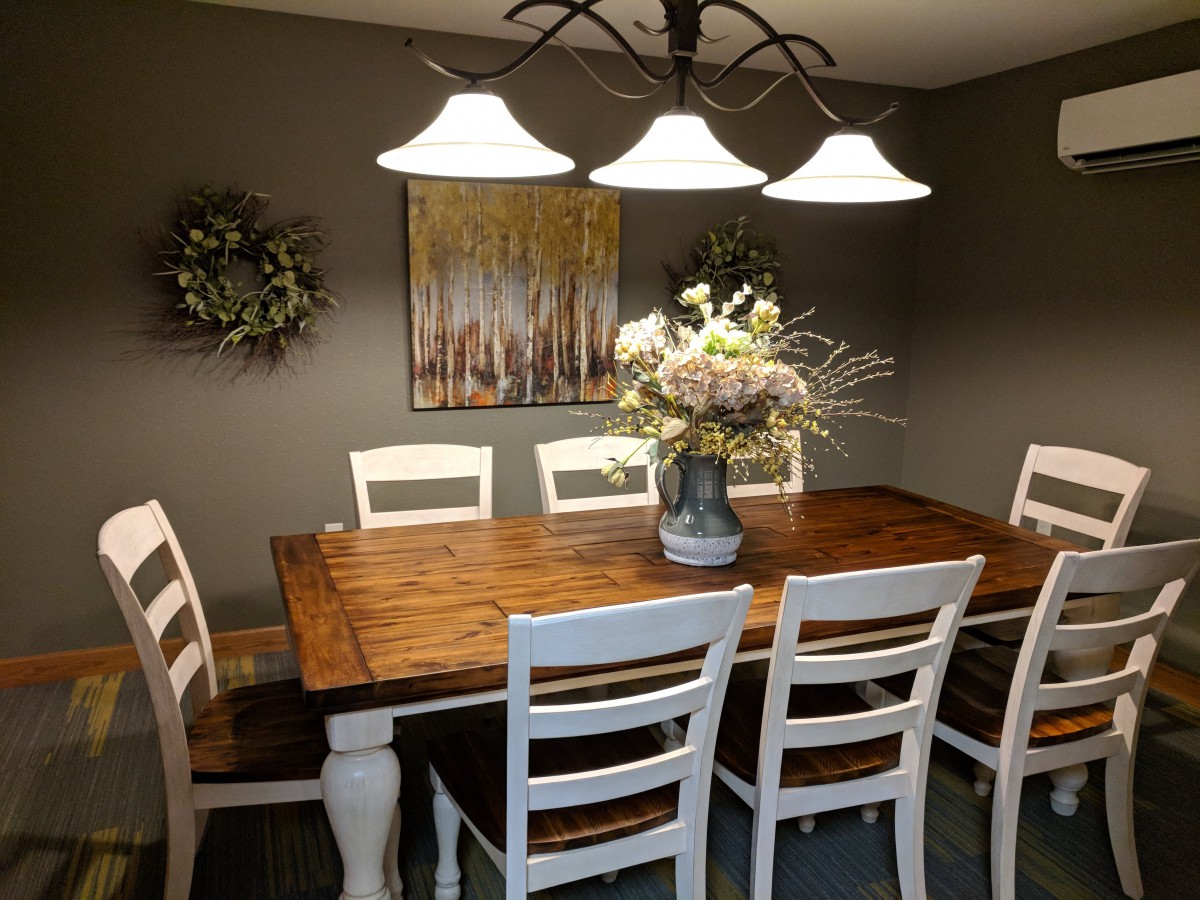 A cozy dining room with a wooden table, white chairs, and elegant lighting.