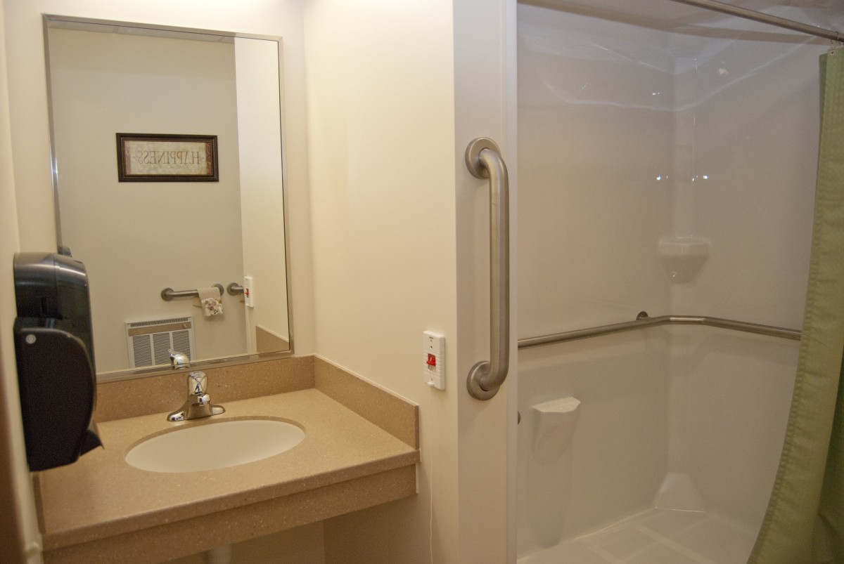 A modern bathroom with a sink, mirror, and accessible shower.